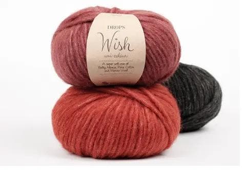 Na zdjęciu znajdują się trzy motki włóczki w kolorach czerwieni i czerni. Czerwone motki są ułożone jeden na drugim, a czarny motek schowany jest za nimi.